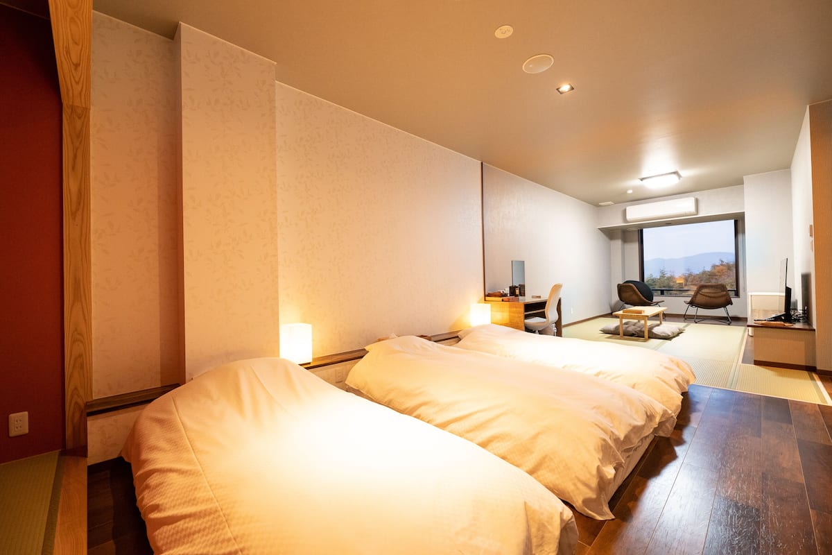 Ein Hotelzimmer mit zwei Betten, einer Sitzecke mit Blick und einem großen Fenster.
