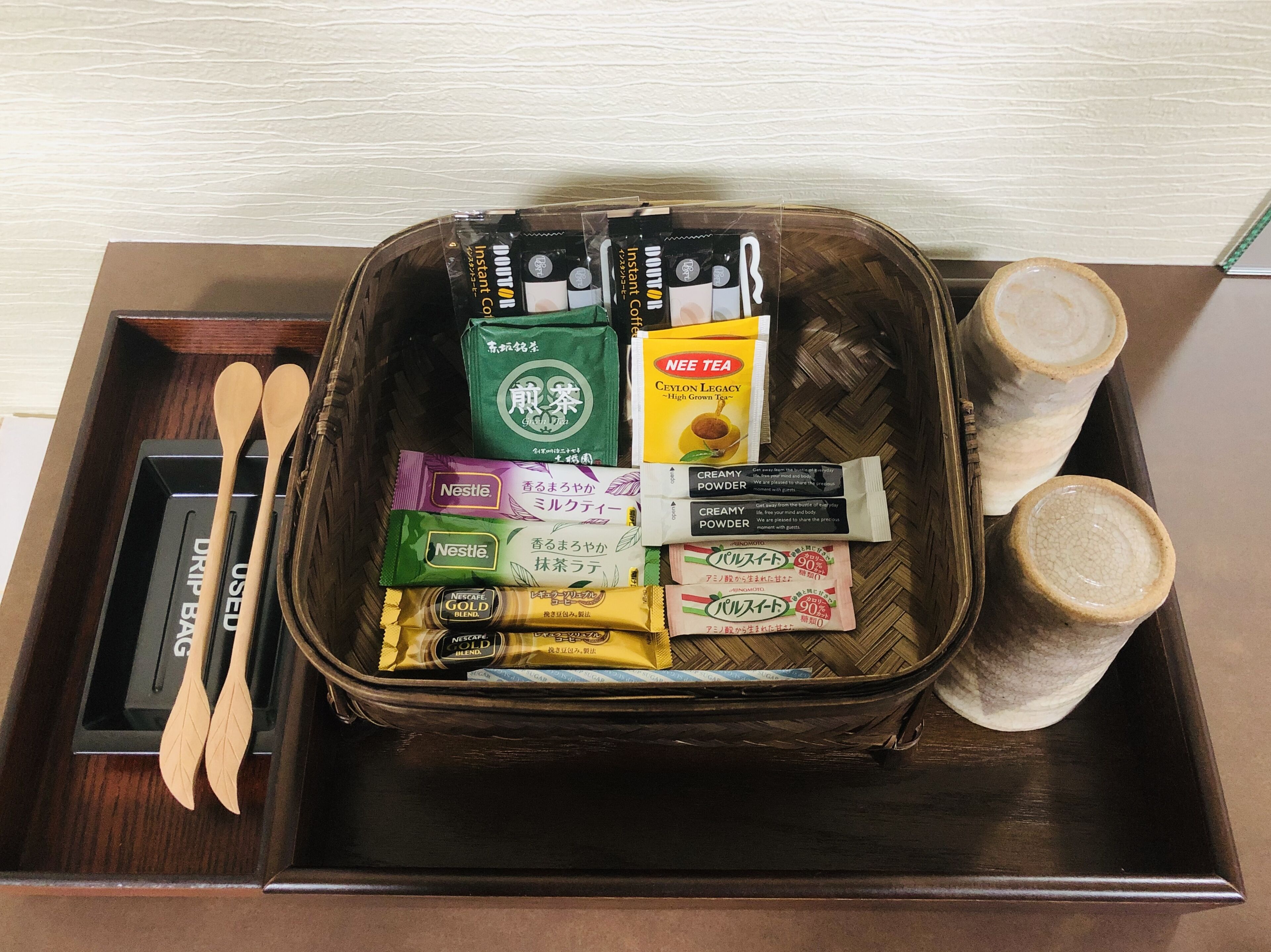 Un plateau avec des sachets de thé, une boîte étiquetée « SACHETS À INFUSER » et des cuillères en bois.
