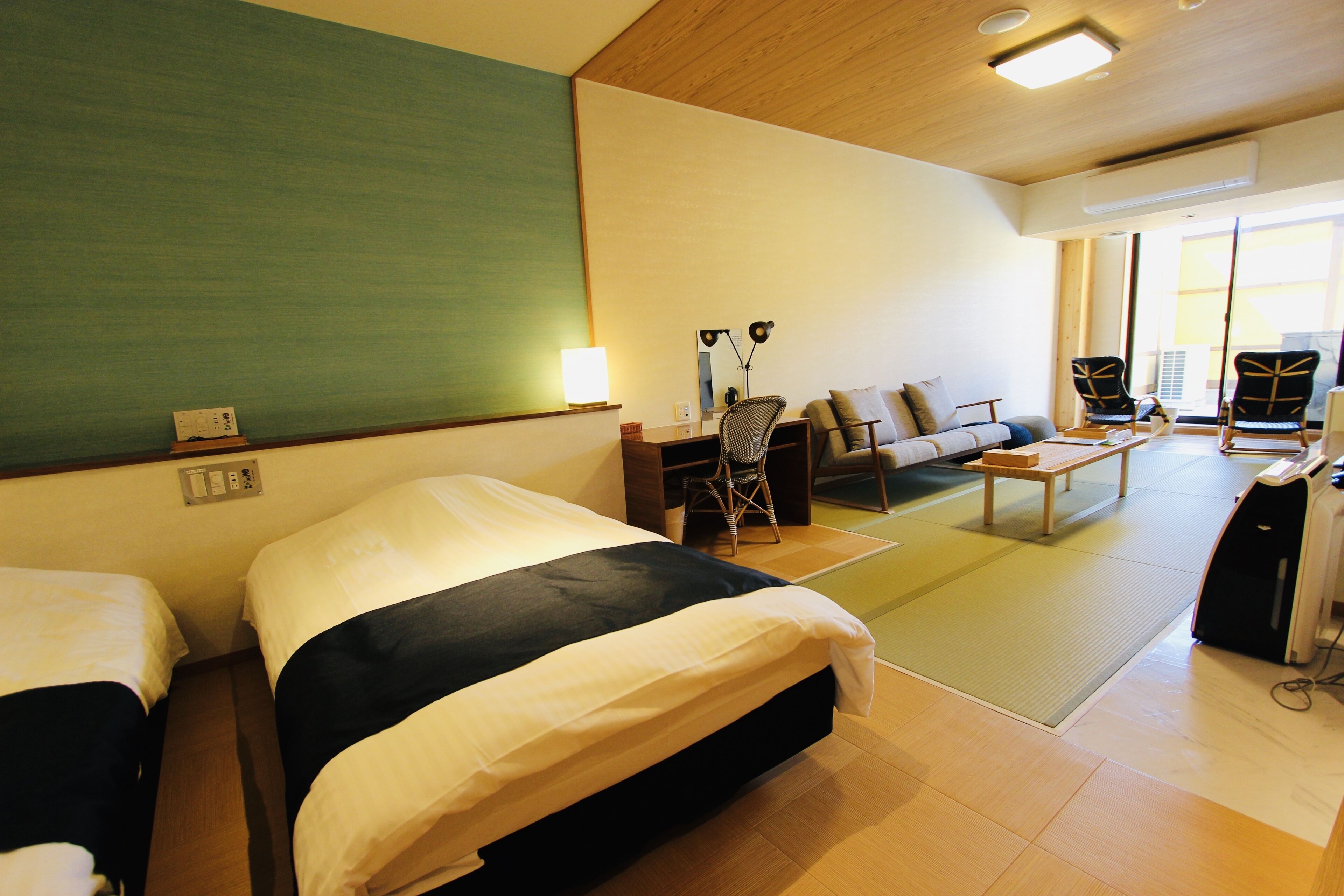 A hotel room with two beds, a sofa, a desk, and a chair.