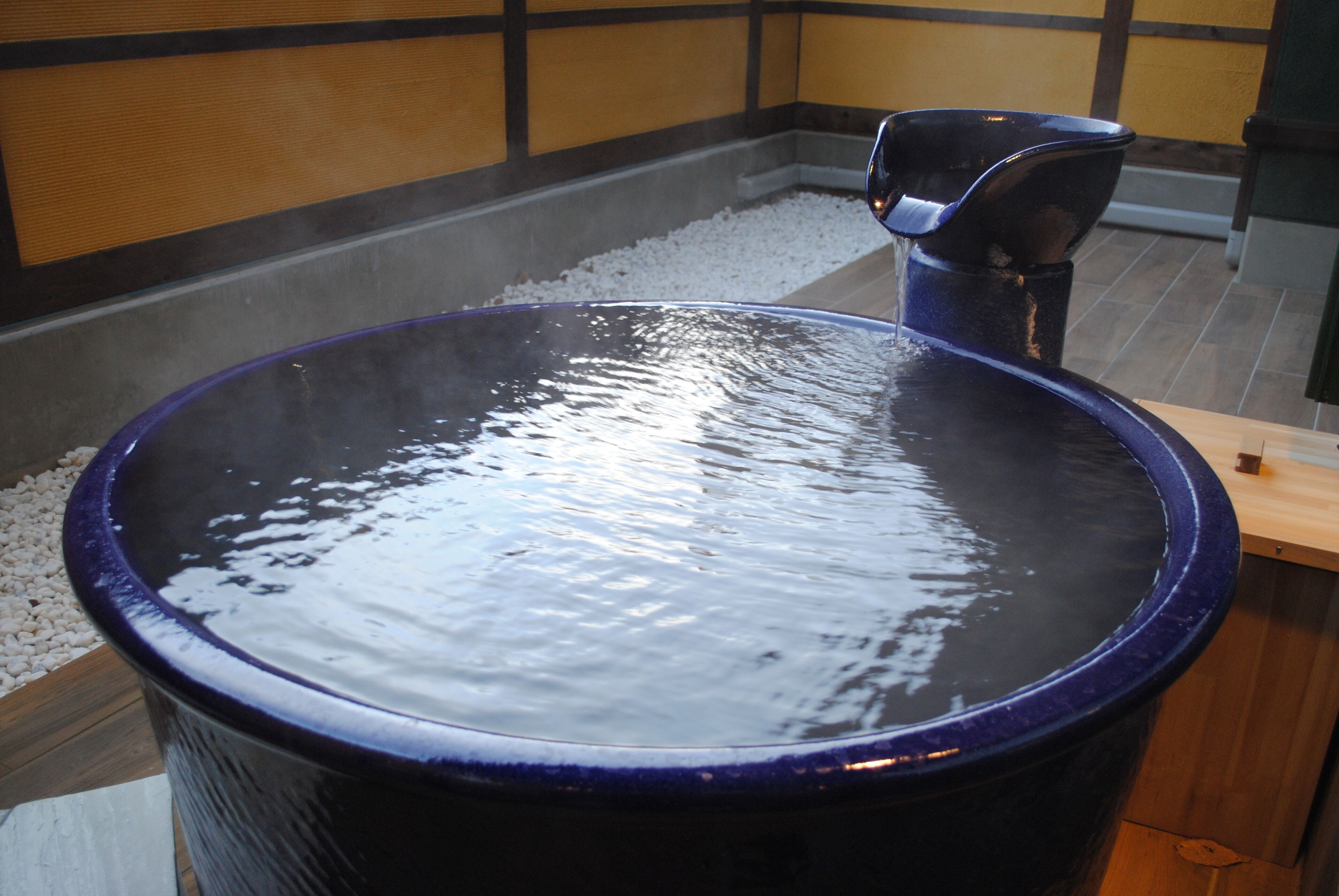 Een warmwaterbronbad met een blauw bassin en een zwarte stoel.