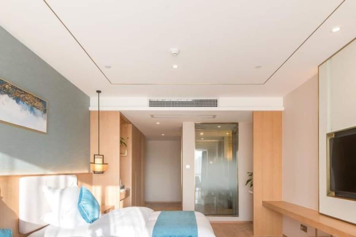 A modern hotel room with a large bed, a TV, and a view of the hallway.