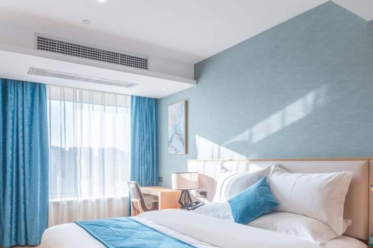 A modern hotel room with a large bed, a desk, and a chair.