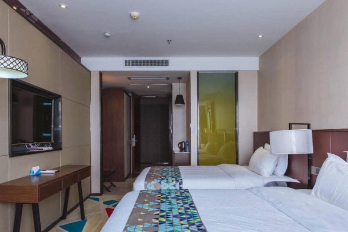 A hotel room with a large bed, a desk, a TV, and a bathroom visible through an open door.