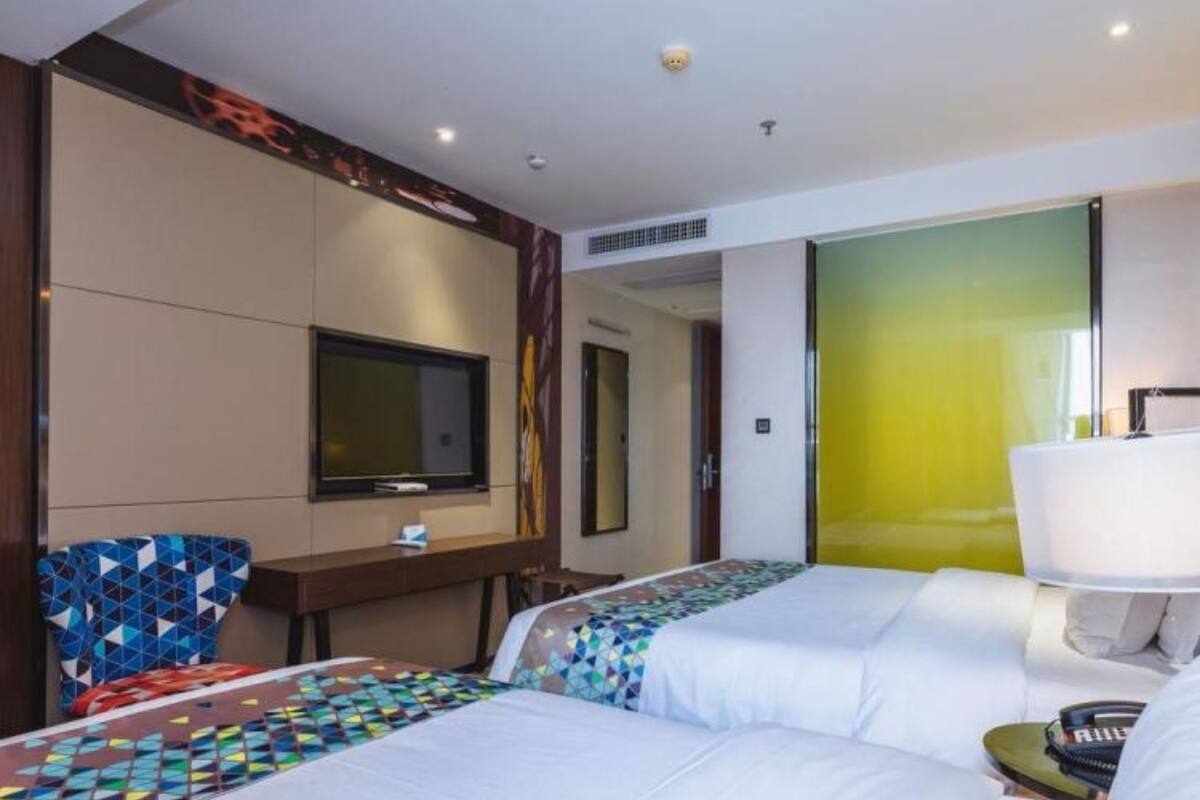 A hotel room with two beds, a TV, a desk, and a chair.