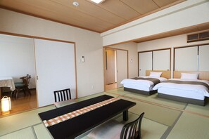 A hotel room with tatami flooring, a low table, two beds, and a sliding door. - Bardenya Soho (Zao)