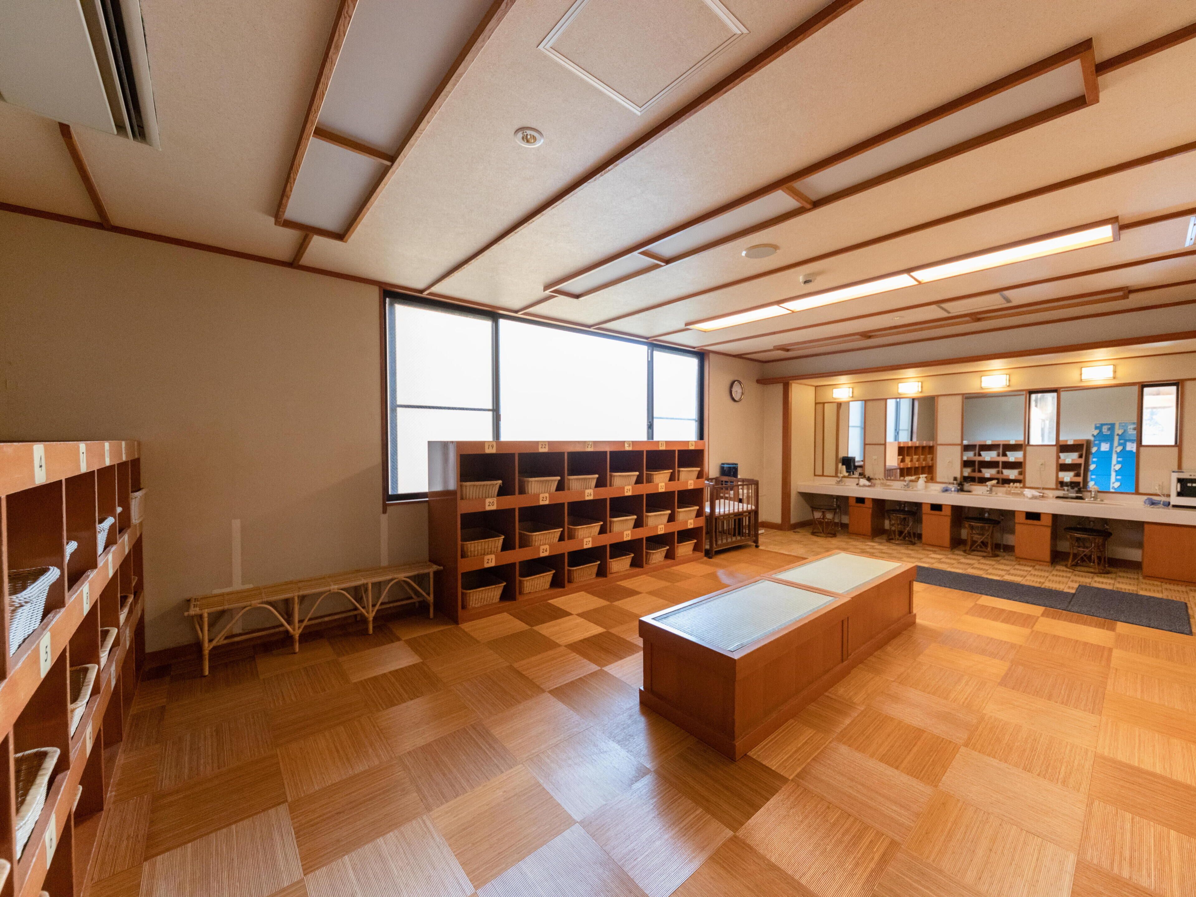 Una biblioteca con suelos de madera, estanterías, un banco y un amplio ventanal.