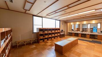 A library with wooden floors, bookshelves, a bench, and a large window.