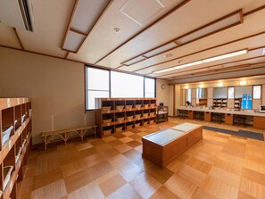 A library with wooden floors, bookshelves, a bench, and a large window. - Bardenya Soho (Zao)