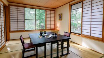 A traditional Japanese room with tatami flooring, a low table with dishes, and shoji screens.