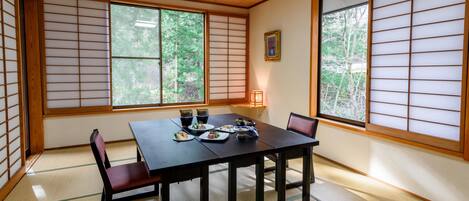 A traditional Japanese room with tatami flooring, a low table with dishes, and shoji screens.