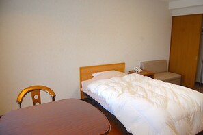 A hotel room with a bed, a wooden chair, a small table, and a nightstand with a phone. - Bardenya Soho (Zao)