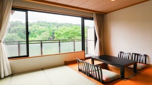 A room with tatami flooring, a low table with chairs, and a large window with a view of greenery. - Bardenya Soho (Zao)