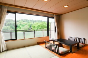 A room with tatami flooring, a low table with chairs, and a large window with a view of greenery. - Bardenya Soho (Zao)
