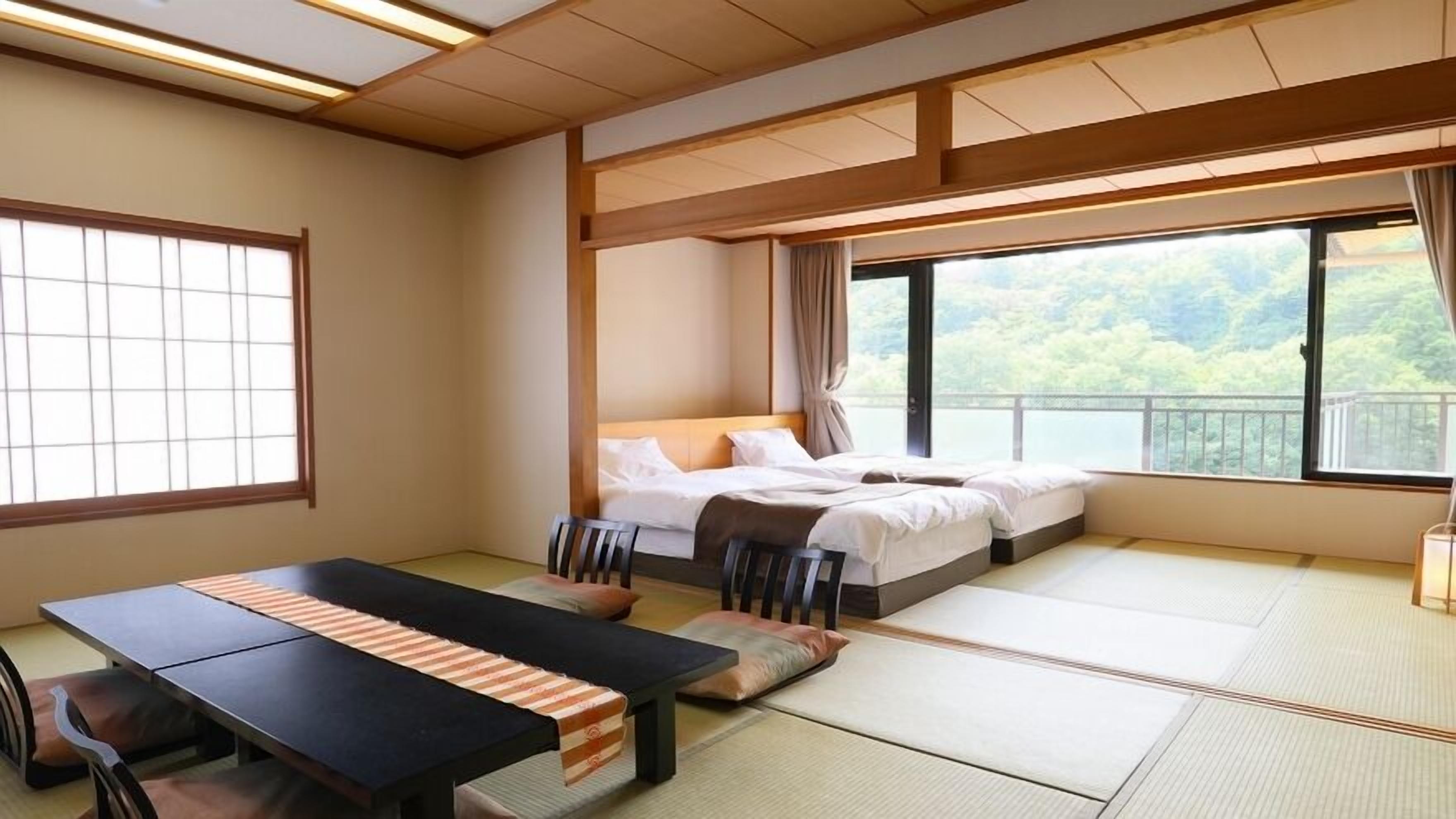 A traditional Japanese-style room with tatami flooring, a low bed, a dining table with cushions, and large windows offering a view of greenery.