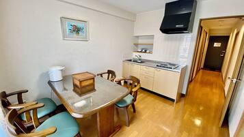 A compact kitchen with a dining table, chairs, a stove, and a sink.