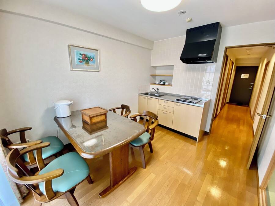 A compact kitchen with a dining table, chairs, a stove, and a sink.