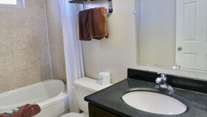 A bathroom with a bathtub, toilet, sink, and mirror.