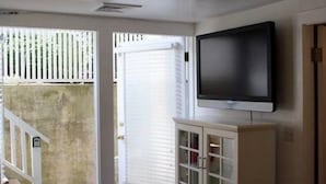 A room with a television mounted on the wall, a cabinet below it, and a door leading to an outdoor area with a white fence. - Extend your rest in the Wellesley Square's best (Wellesley)