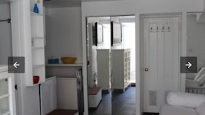 A modern kitchen with white cabinetry, a small refrigerator, and a dining area with a white table and chairs. - Extend your rest in the Wellesley Square's best (Wellesley)