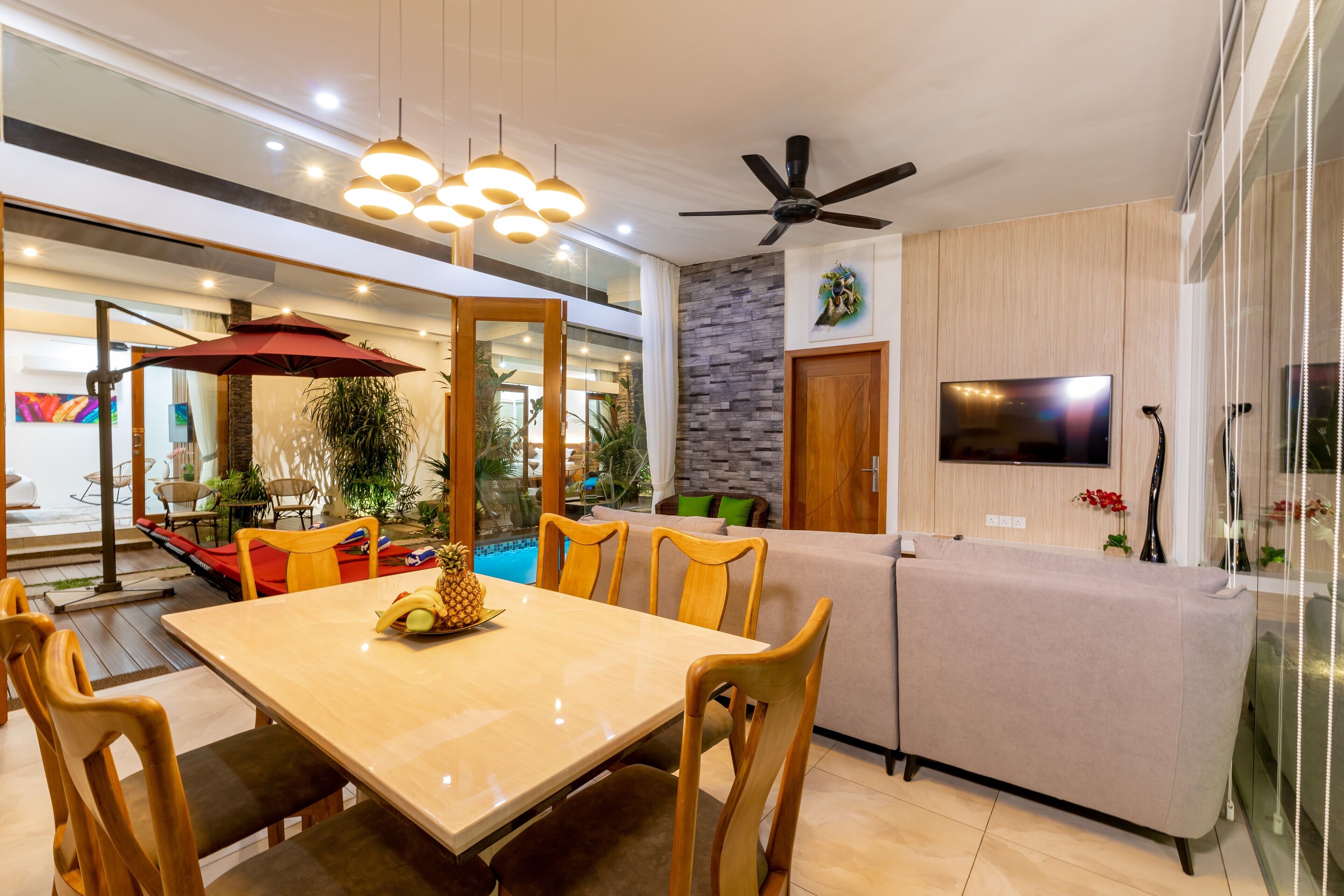 A modern living room with a dining area, a pool, and a TV.