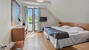 Une chambre avec un lit, un bureau, une télévision et une vue sur l’extérieur.