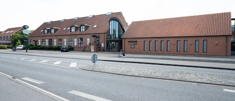 En byggnad med en fasad av tegel, stora fönster och en modern entré.