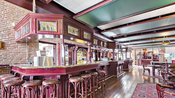 Un coin bar avec des tabourets en bois, un mur en briques et un tapis à motifs.