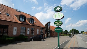 Un hôtel avec un toit recouvert de tuiles rouges, une enseigne indiquant « FILSO », et une autre indiquant « HOTEL PUB BOWLING » et « Restaurant ».