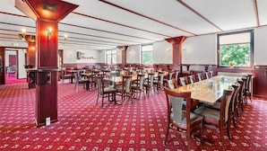 Une grande salle de conférence dotée d’une longue table et de nombreuses chaises, d’un sol recouvert de moquette et de quelques éléments décoratifs en bois.