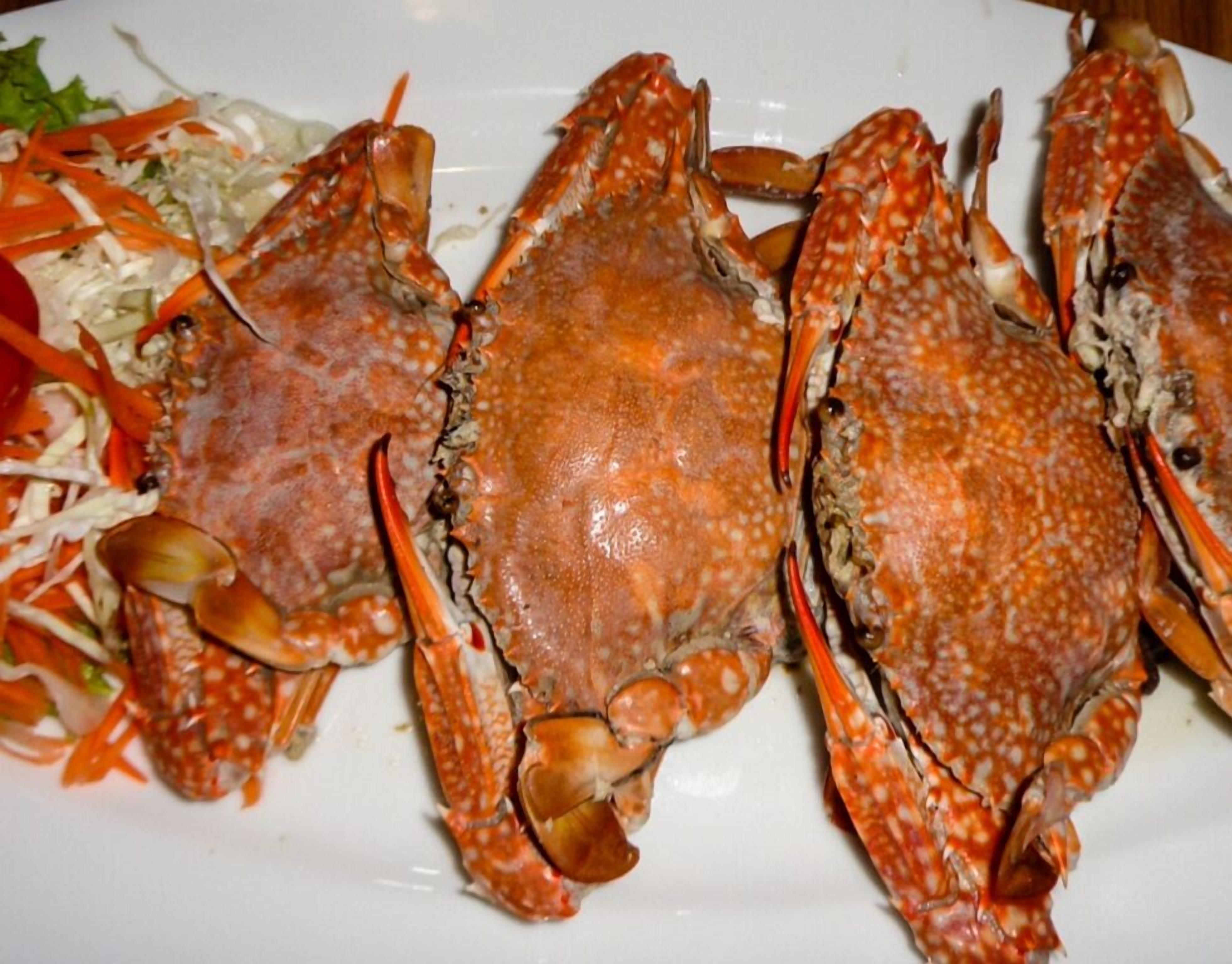 A plate with three cooked crabs and a side salad.