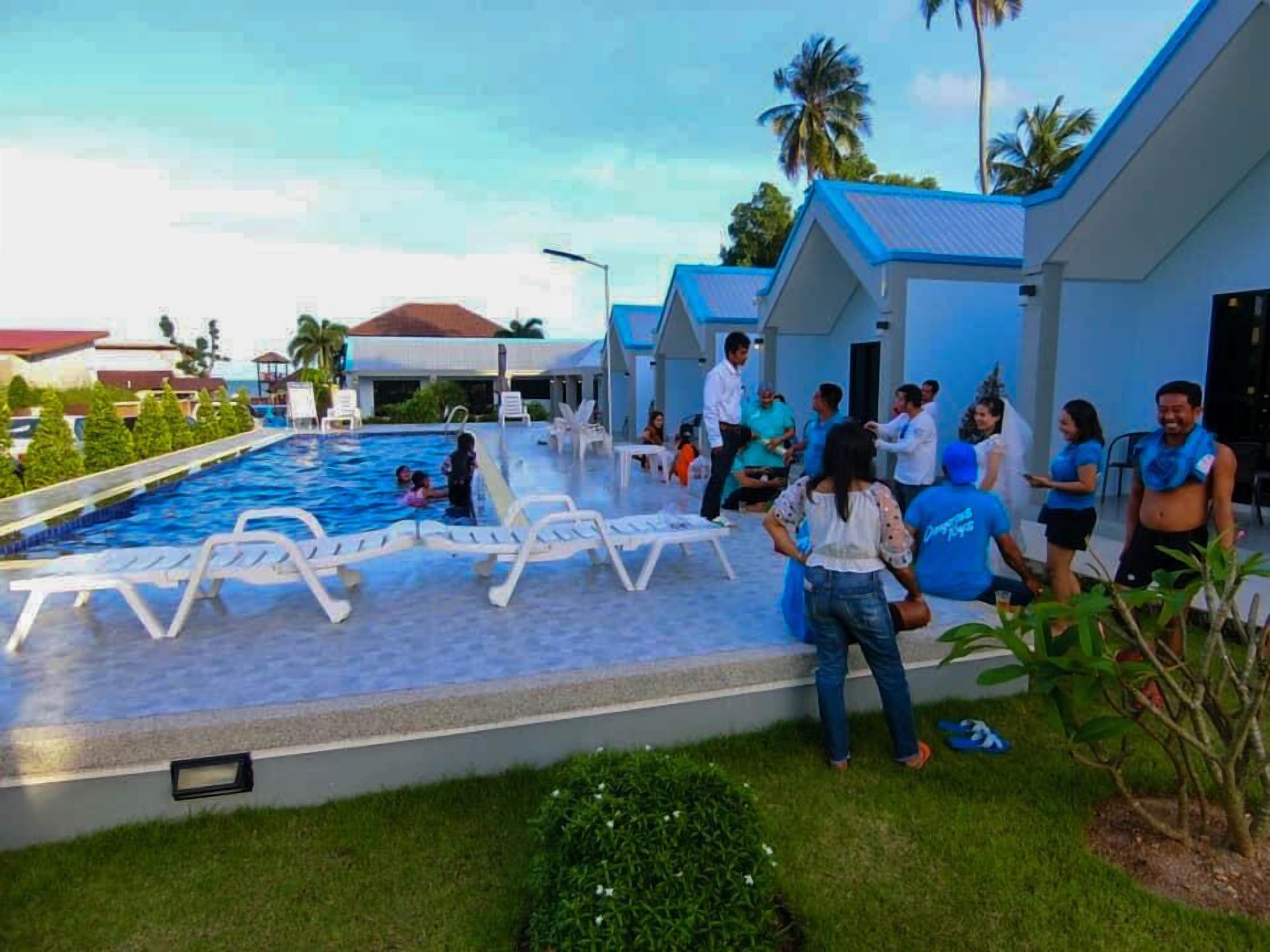 Un espace piscine comprenant des chaises longues, une piscine et un bâtiment doté d’un toit bleu.