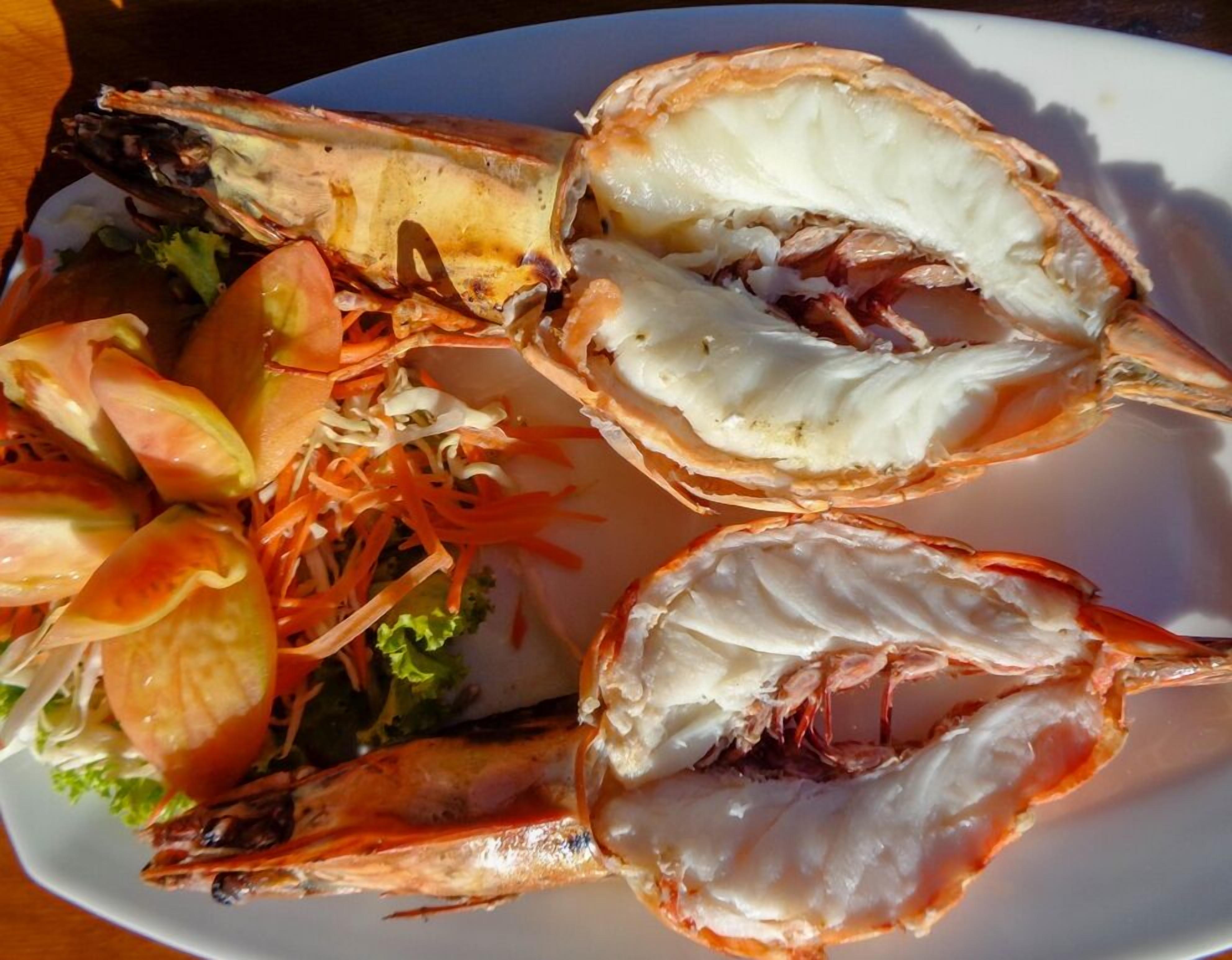 A plate of cooked lobsters with a side salad.