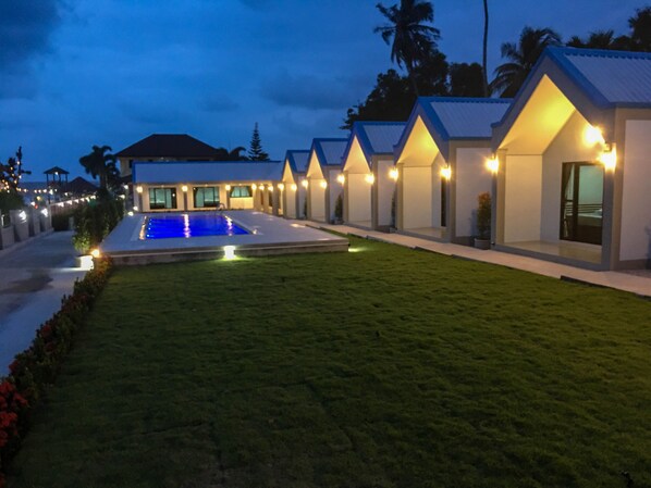 A modern resort with a swimming pool, well-maintained lawns, and multiple guest villas with outdoor lighting. - CC Beach Resort (Khanom)