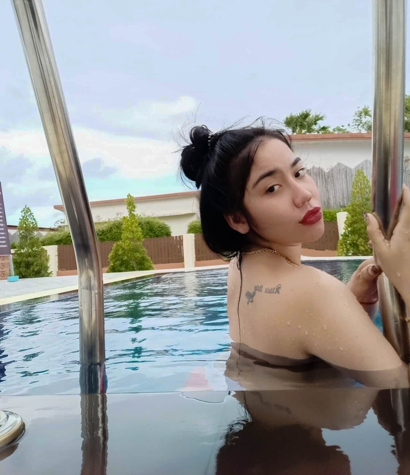 Una persona en una piscina con barandales metálicos, una cerca y follaje al fondo.