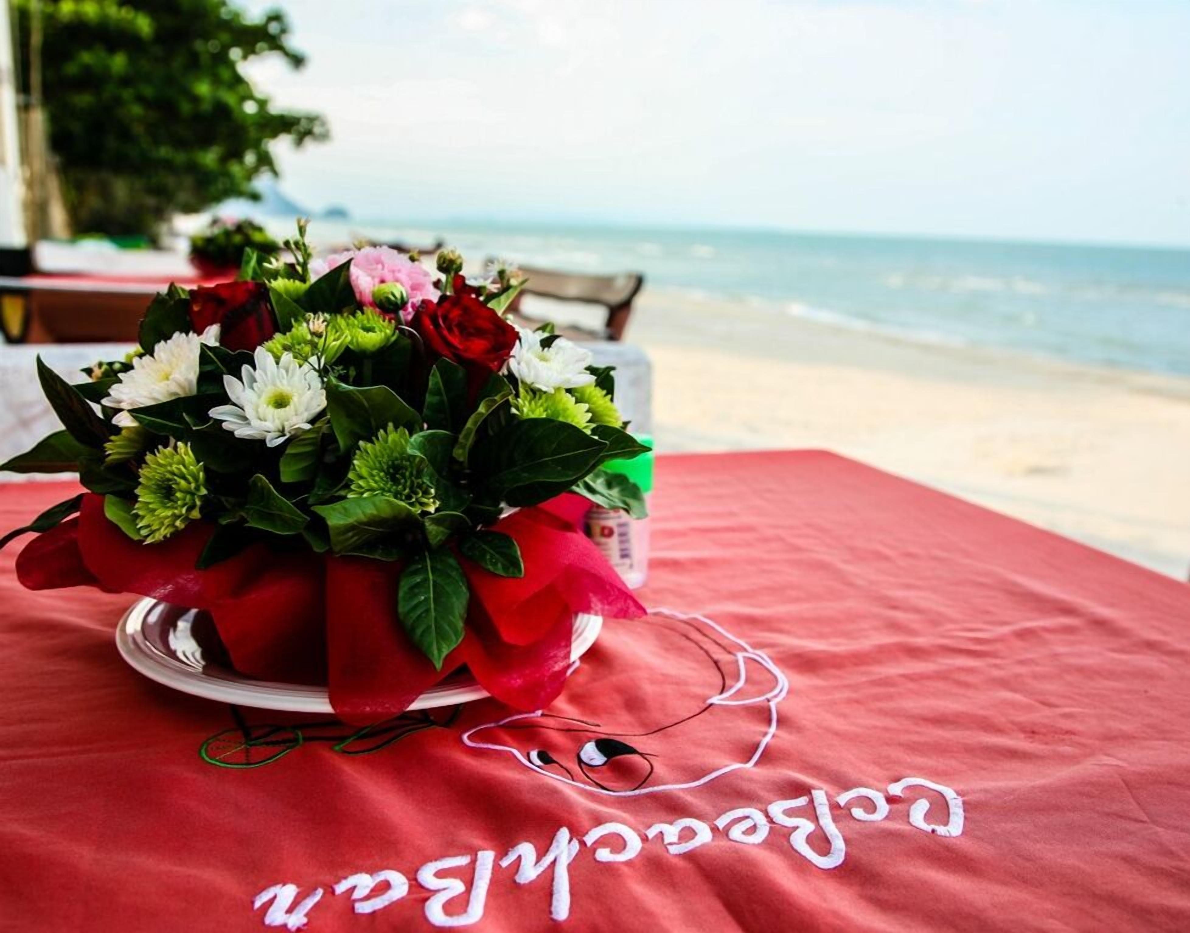 Una mesa con mantel rojo y un ramo de flores.