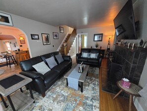 A living room with a black leather sofa, a coffee table, and a fireplace.