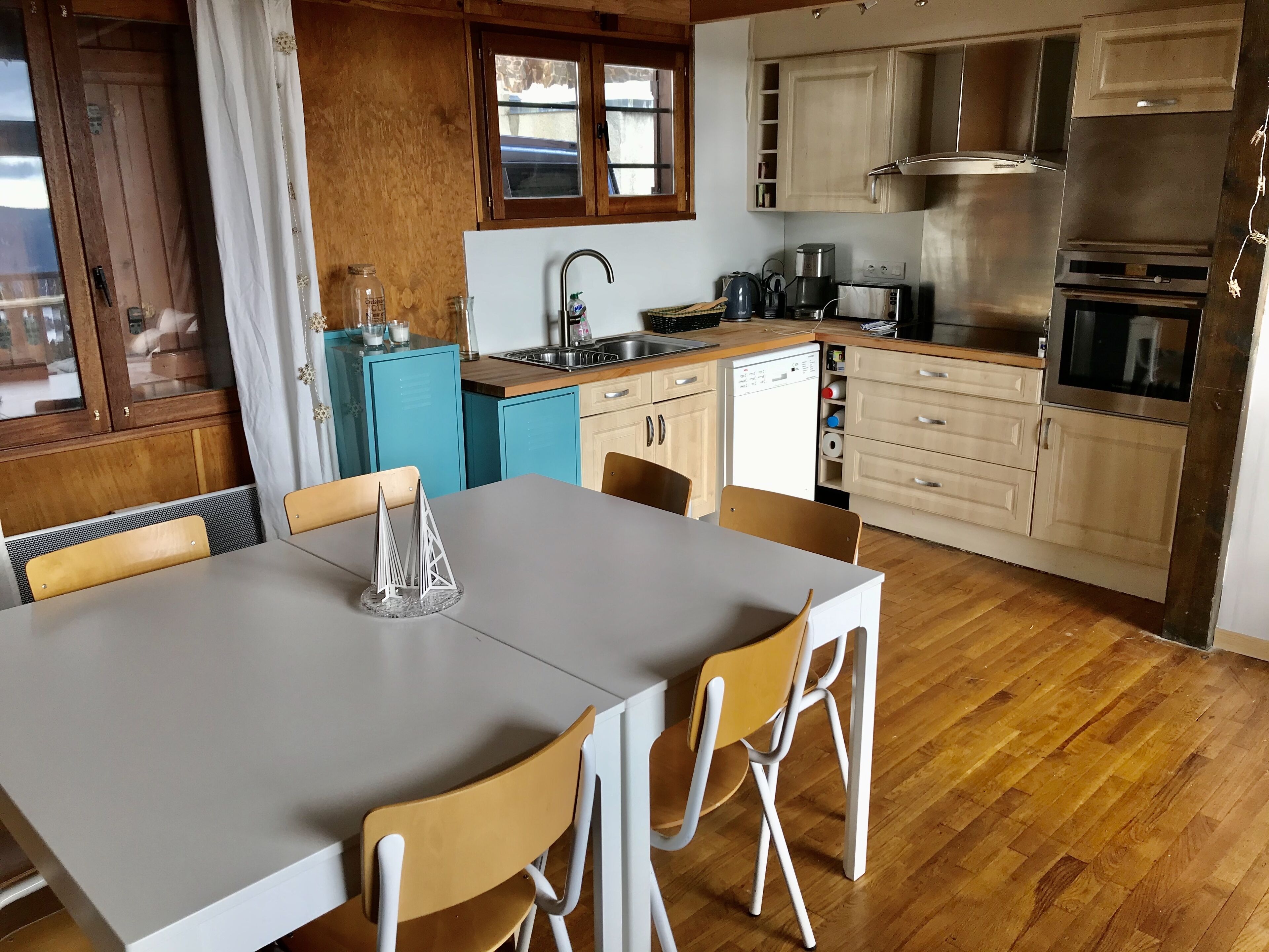 A compact kitchen with a dining area, featuring a sink, stove, and a dishwasher.