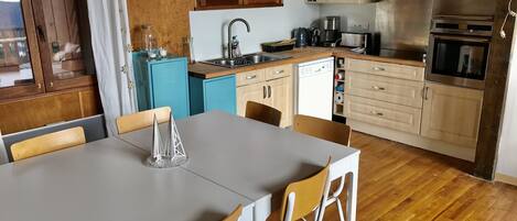 A compact kitchen with a dining area, featuring a sink, stove, and a dishwasher.