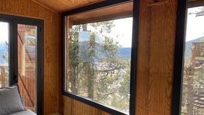 A room with a large window, wooden walls, and a bed with pillows. - Chalet Les Angles 1900m (Les Angles)