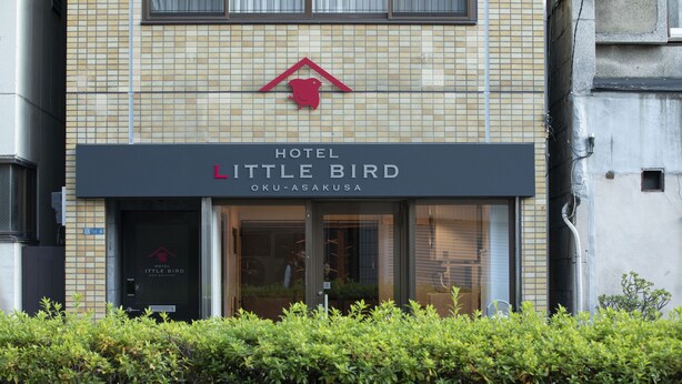 Un hôtel appelé « Hotel Little Bird », avec une façade recouverte de carreaux et un logo au-dessus de l’entrée.