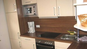 Eine kompakte Küche mit Mikrowelle, Kaffeemaschine, Backofen und Spüle.