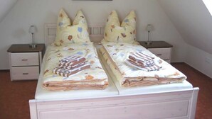 Ein Doppelbett mit Blumenmuster-Bettwäsche, zwei Nachttische mit Lampen, ein gerahmtes Bild an der Wand und eine geneigte Decke.