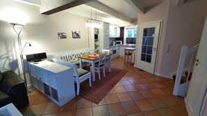 A compact kitchen with white cabinets, a dining table, and a small seating area. - Boowen Taarep 19, Germany (Utersum)