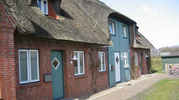 A traditional brick building with a thatched roof, a green door, and a small window. - Boowen Taarep 19, Germany (Utersum)
