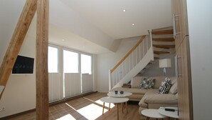A spacious living area with a wooden staircase, a sofa set, and a coffee table. - Am Wasser OG, Germany (Hörnum (Sylt))