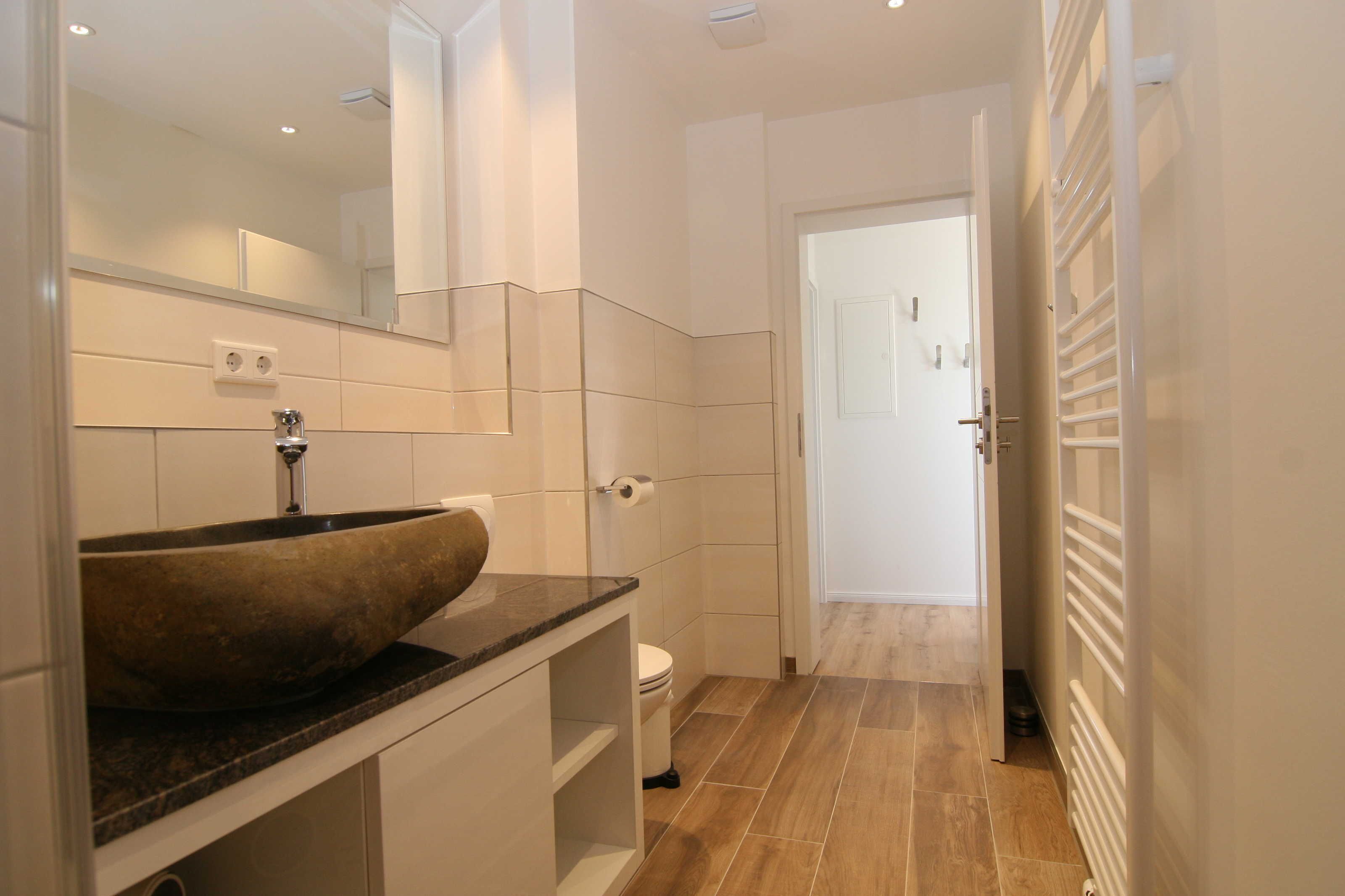 A modern bathroom with a large vessel sink, a mirror, and a toilet.