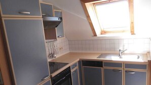A compact kitchen with a built-in oven, a dishwasher, and a window above the sink.