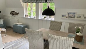 A dining area with a wooden table, wicker chairs, and a hanging pendant light. - Neiwoi 2c, OG, Germany (Borgsum)