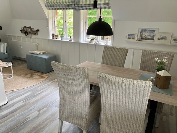 Un coin repas avec une table en bois, des chaises en osier et une suspension décorative.