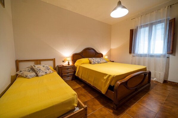 A bedroom with two beds, wooden headboards, a nightstand with a lamp, and a window with curtains. - Le Isole with large terrace overlooking the sea (Campo nell'Elba)